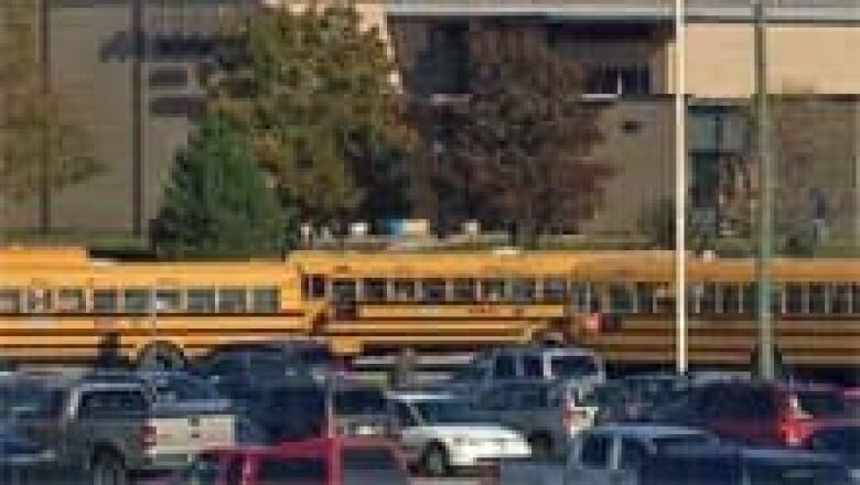 A parking lot full of school buses and cars.