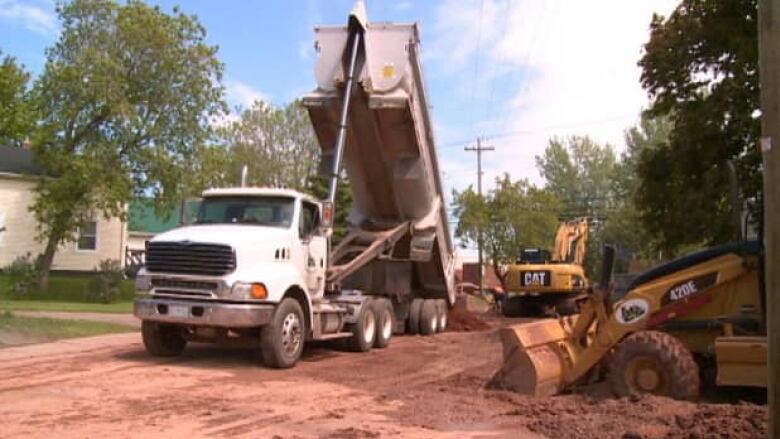 Construction crews tear up the road to install new water and sewer pipes.