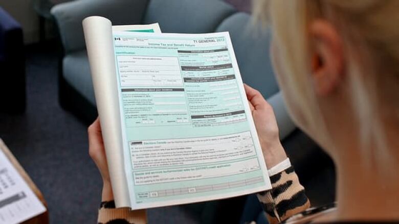 A woman holds a Canadian income tax document known as a T1