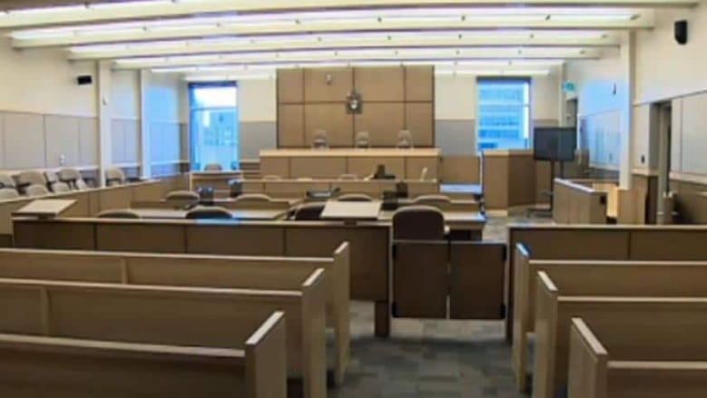 Several rows of wooden benches in the foreground, desks and chairs in the middle and an elevated wooden bench in the background. 