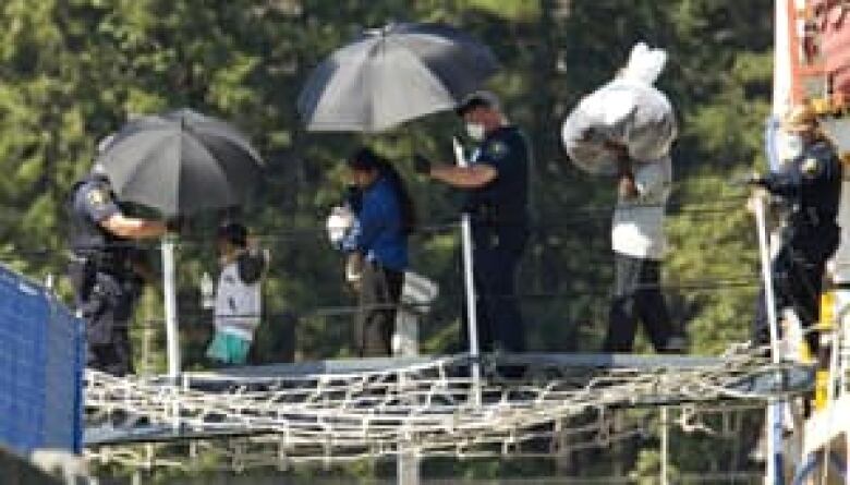 Authorities escort a Sri Lankan family off the MV Sun Sea, the cargo ship that was intercepted off the coast of B.C. in 2010 with 490 would-be refugee claimants aboard.  