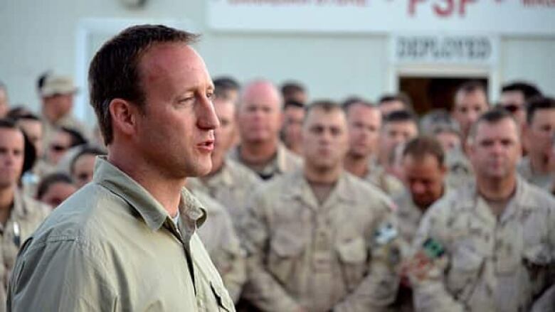 A man speaks to a group of soldiers.