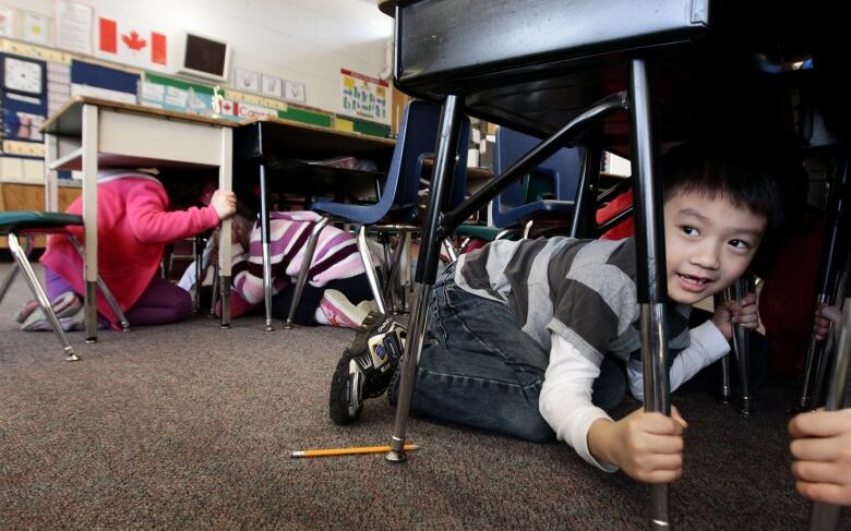 Schoolchildren hide under classroom desks during an earthquake drill