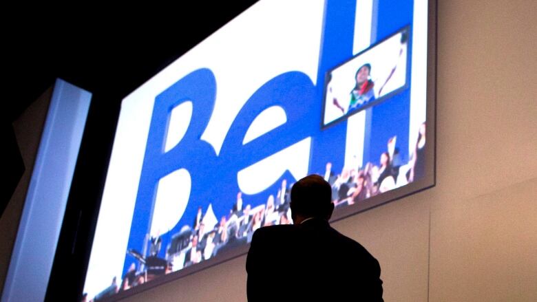 A man looks at a Bell Canada sign.