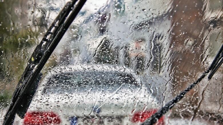 A wet windshield and windshield wipers are seen from within a vehicle.