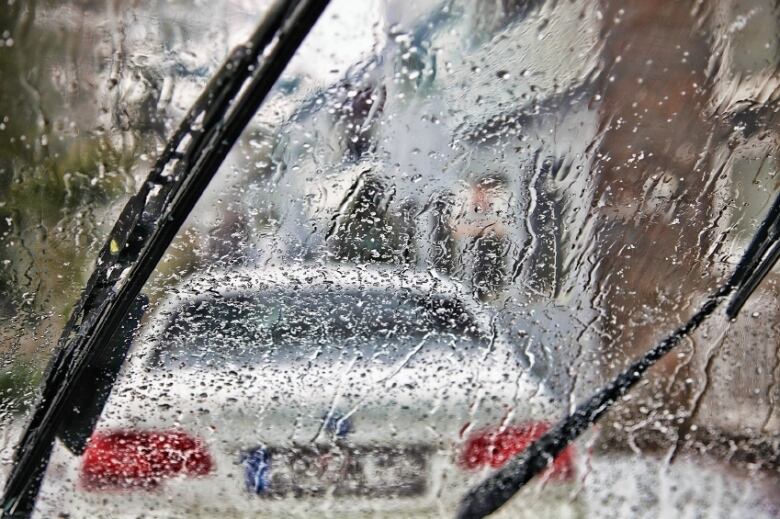 A wet windshield and windshield wipers are seen from within a vehicle.