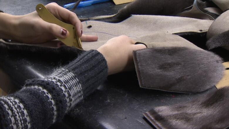 A person making seal skin mitts.