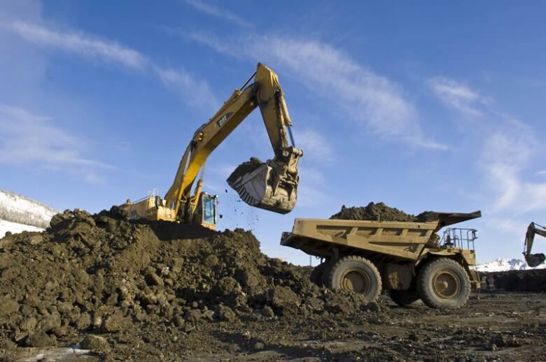 Heavy machinery are seen loading rock into a truck at a mine site.