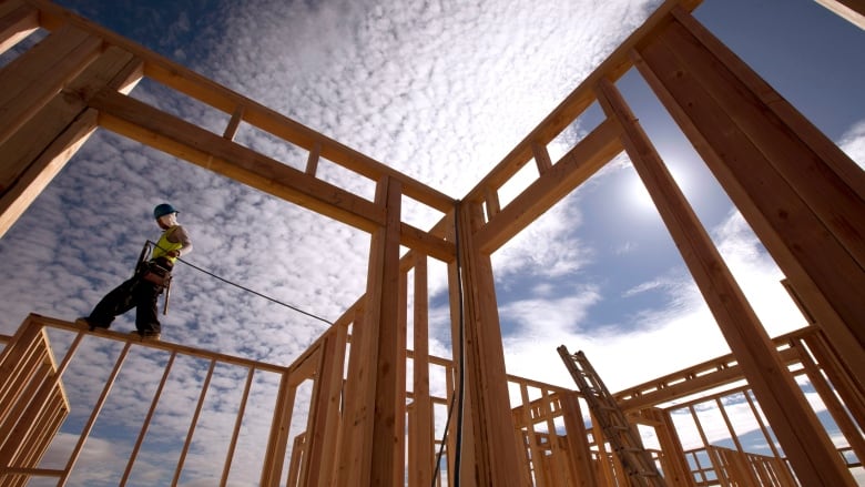 A construction worker walks atop a wood frame for a building.