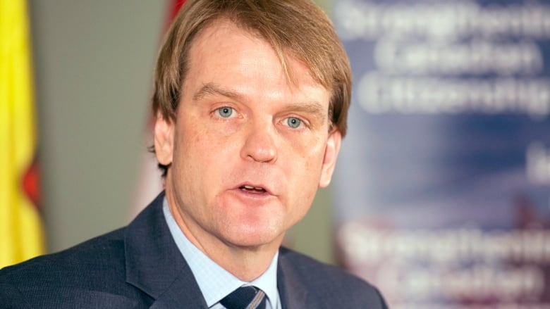 A stately man with reddish-brown hair speaks at a press conference.