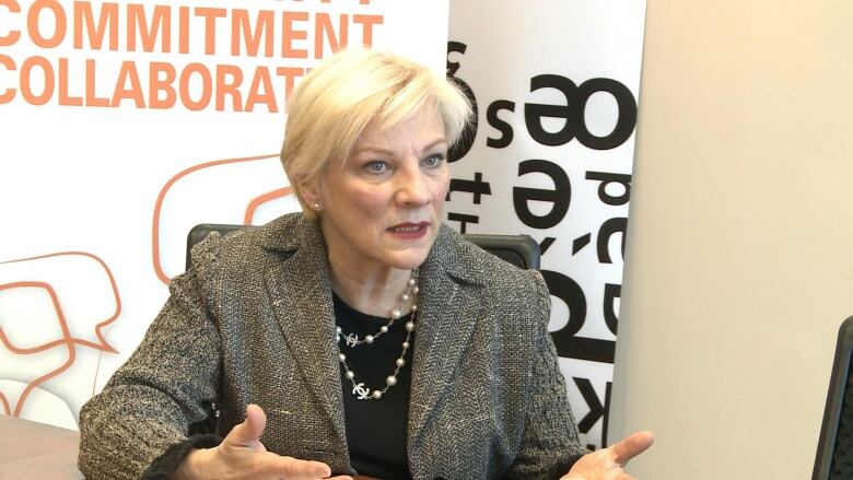 A woman sits behind a desk.