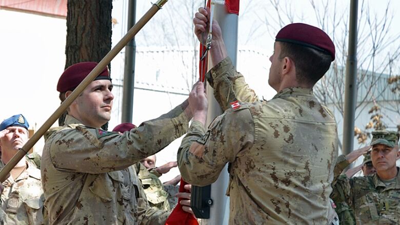 Cpl. Harry Smiley (L) and Cpl . Gavin Early take down the Canadian flag for the last time in Afghanistan on Wednesday March 12, 2014, bringing an end to 12 years of military involvement that cost the lives of 158 soldiers. 