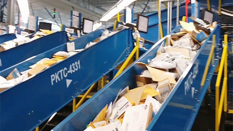 Blue conveyor troughs filled with letters and parcels.