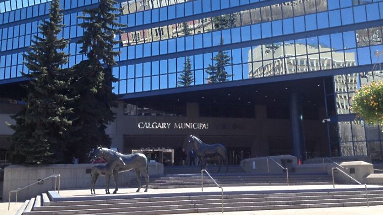 A blue sky is reflected in a building that has hundreds of glass panes. The building is labelled 'Calgary municipal building.' 