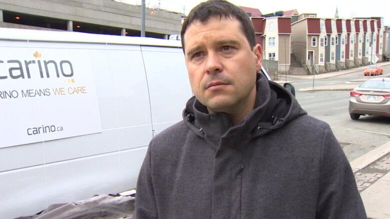 A man stands in front of a shipping van in winter.