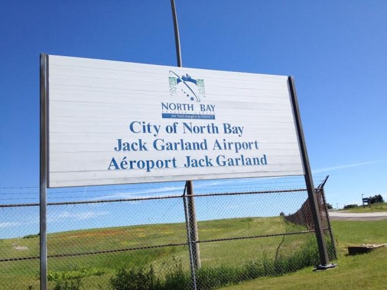 A sign with blue lettering welcoming people to the Jack Garland Airport in North Bay.