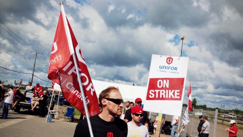 A demonstrator holds up a sign and flag.