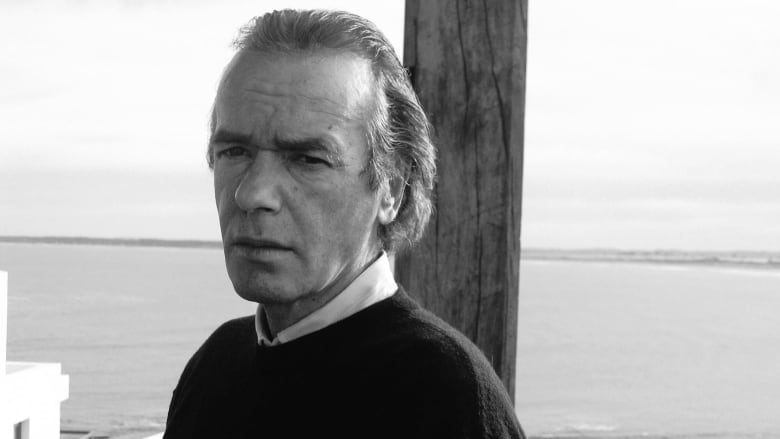 A black and white photo of a man by the water. 