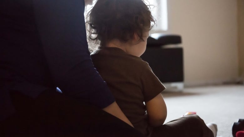 Young child sitting in woman's lap.