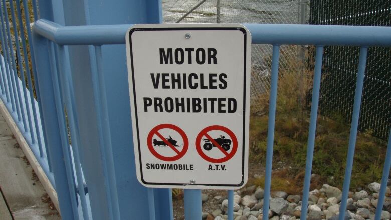 A sign on a blue fence that says Motor Vehicles Prohibited. 