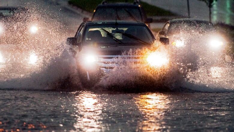 Motorists head through a flooded section of a city street