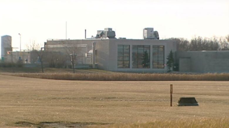 A large industrial building can be seen across a field.