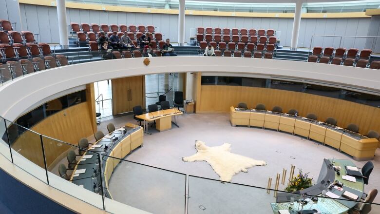 A building with a gallery and seats and tables below.