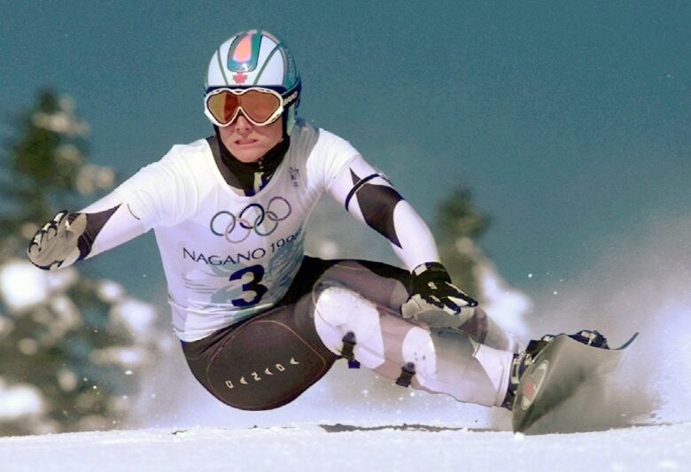 A snowboarder gets low to the ground while navigating his way down a giant slalom course.