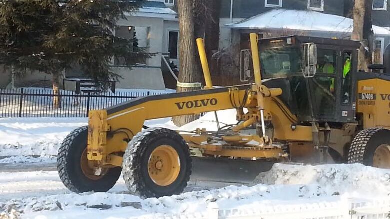 A snow plow works on a city street