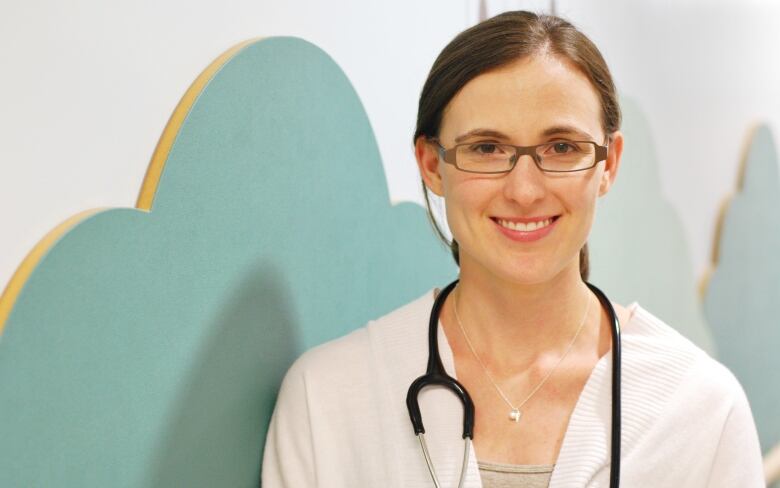 A woman with a stethoscope smiles.