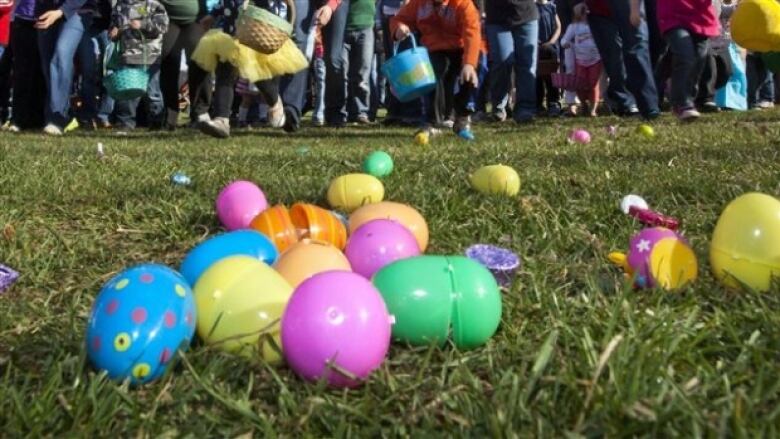 A pile of plastic Easter eggs on the grass in bright colours.