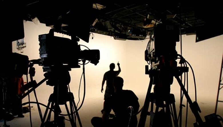 Cameras and people in a lit up studio