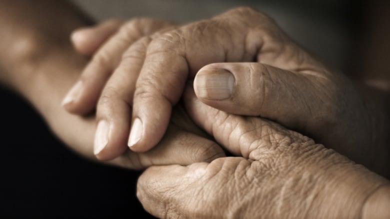 Two hands of elderly persons grasp together. 