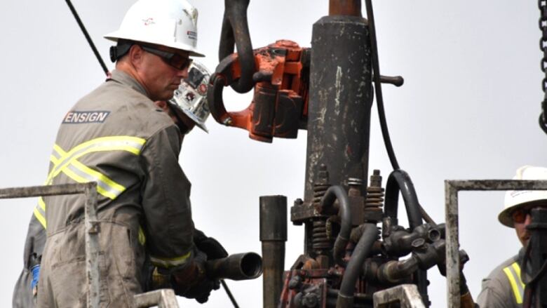 A worker pulls pipe out of the ground at an orphan well site in Alberta.