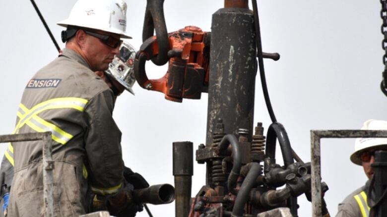 A worker pulls pipe out of the ground at an orphan well site in Alberta.