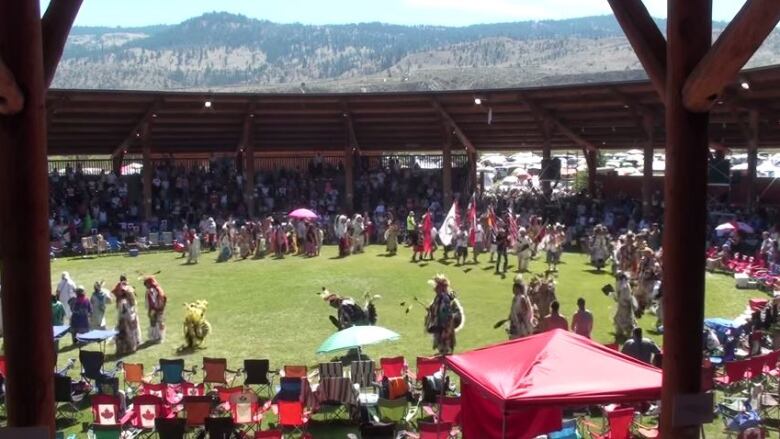 A number of people are seen in a circle, with chairs and fair merchandise around them.