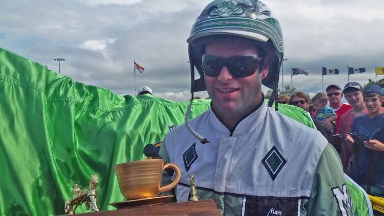 A harness racer holds the Gold Cup and Saucer trophy after a 2015 victory.