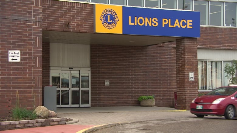 Exterior of a brick building. A yellow and blue sign above a door says Lions Place.