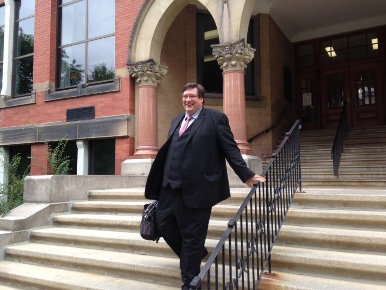 A man walks down the steps of a courthouse