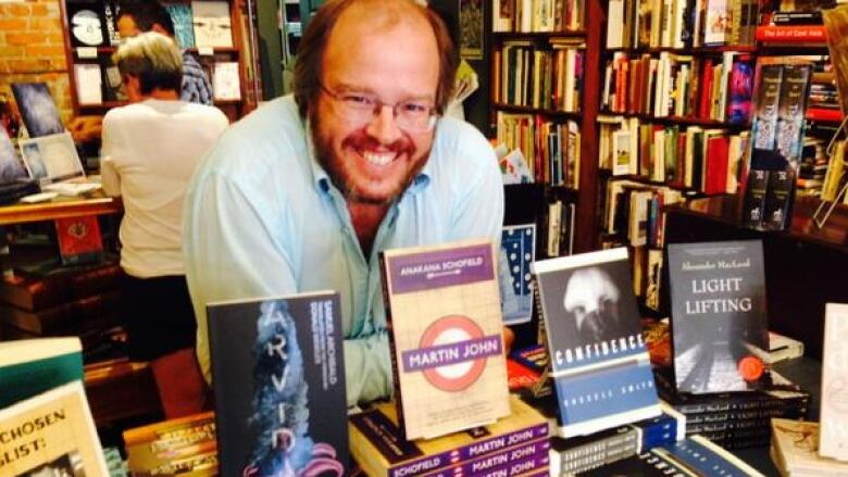 Dan Wells of Biblioasis is seen posing alongside three books that made the Giller Prize short list.