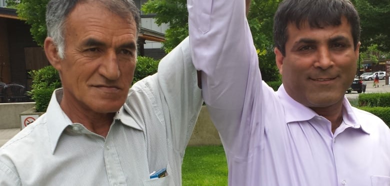 Iraqi Najah Aboud (left) and Iranian Zahed Haftlang hold hands up in the air.