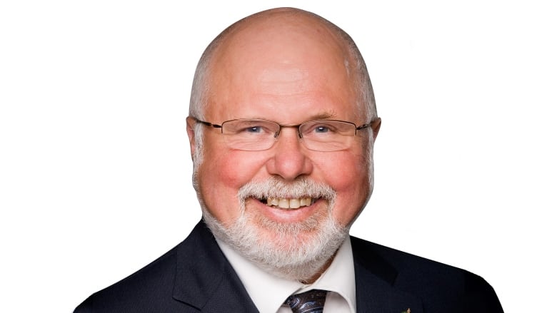 A man in a black suit, purple and blue tie and a white shirt underneath.