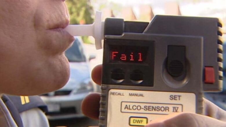 Person blowing into breathalyzer device with the reading 