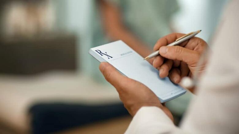 A doctor writes a note on an Rx pad.