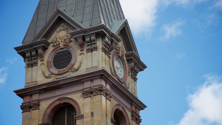 A close-up on the stone clock tower against a blue sky