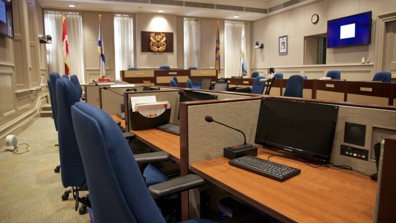 a computer and office chair at a desk in city council chambers