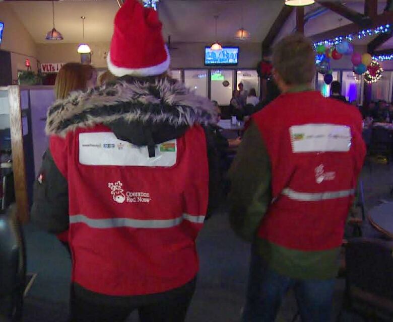 Two volunteers wearing red vests that say 