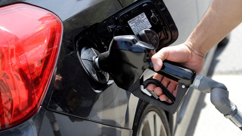 A person pumps gas into a car.