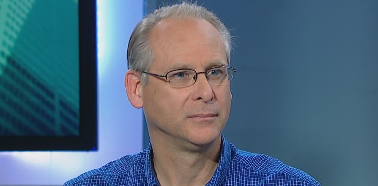 A man in a blue shirt in a TV studio.