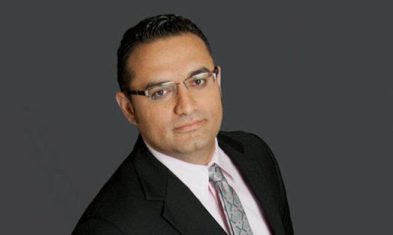 Man in a suit wearing glasses poses for a portrait